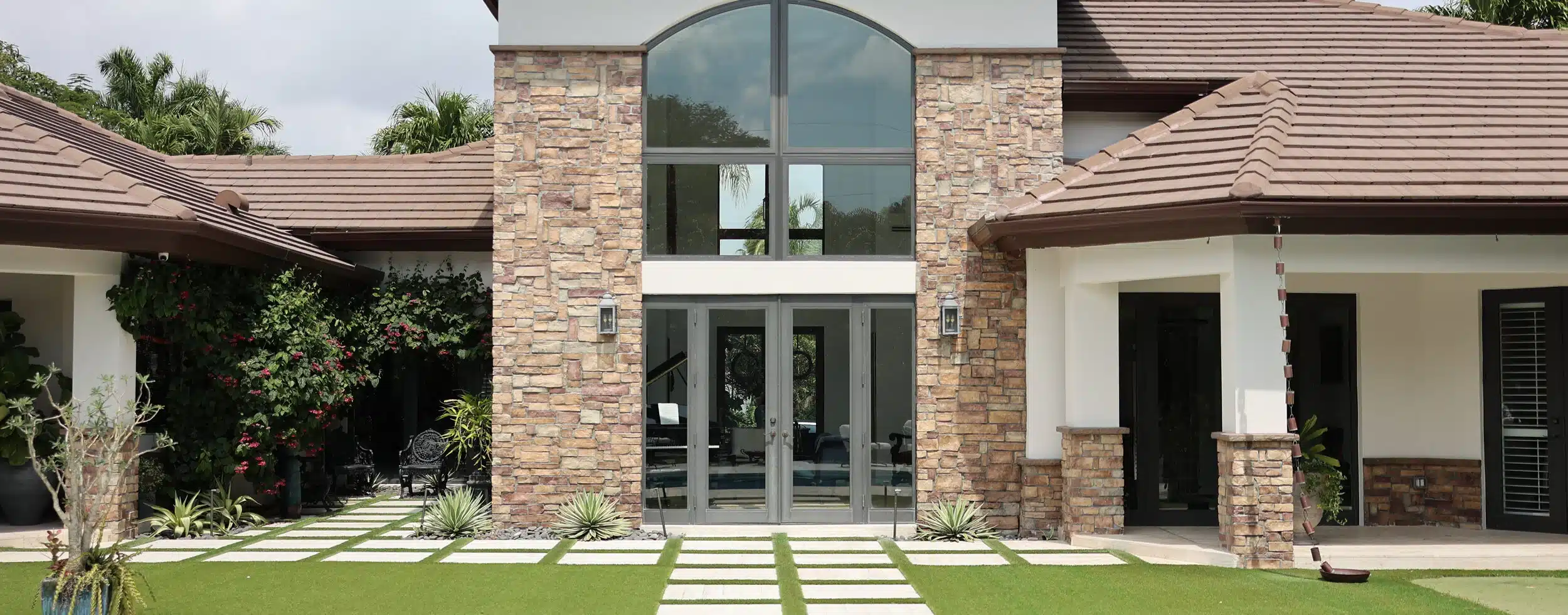 Stone facade home with arched impact window and French doors