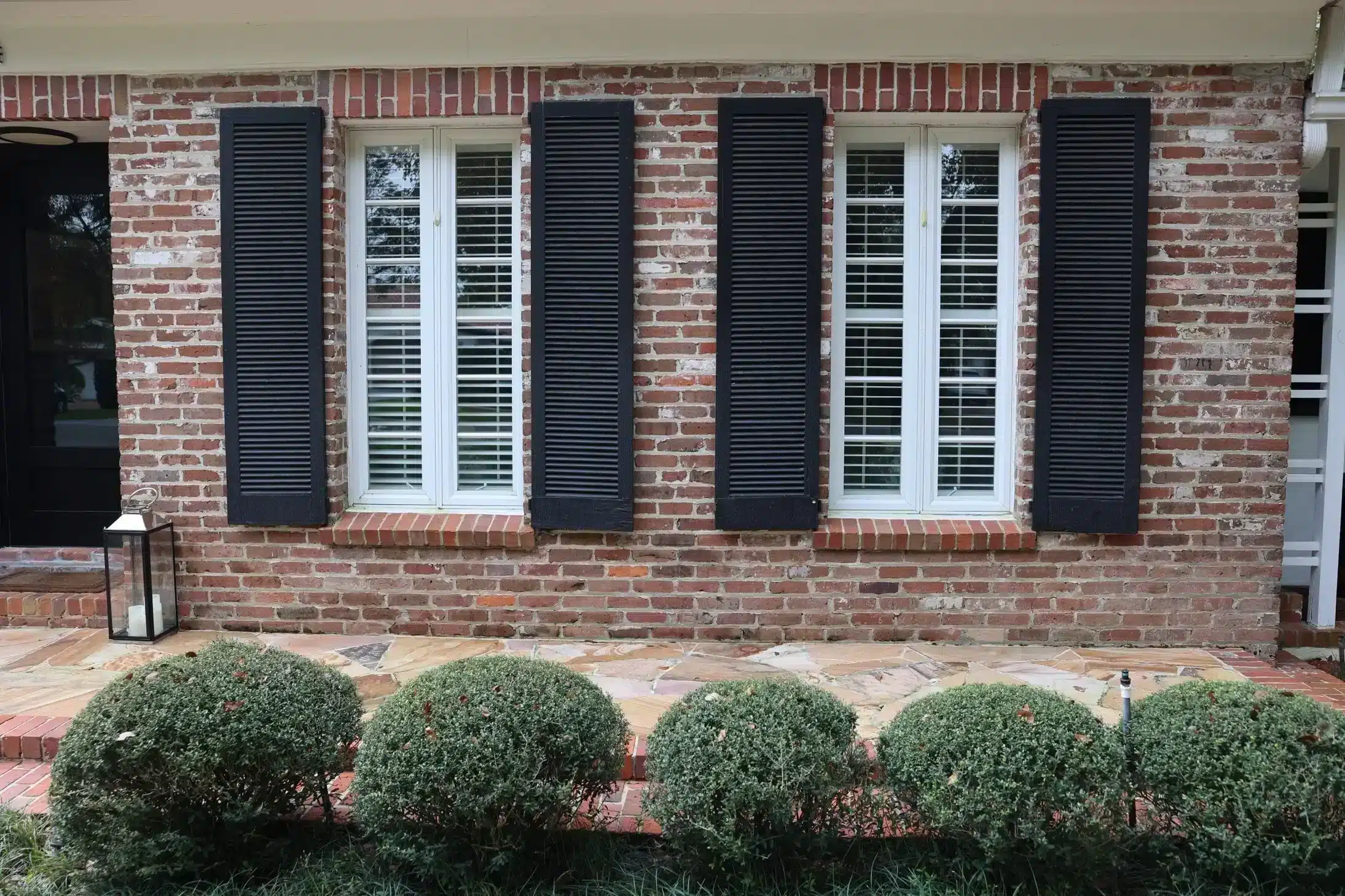 Brick facade with louvered impact windows and shutters