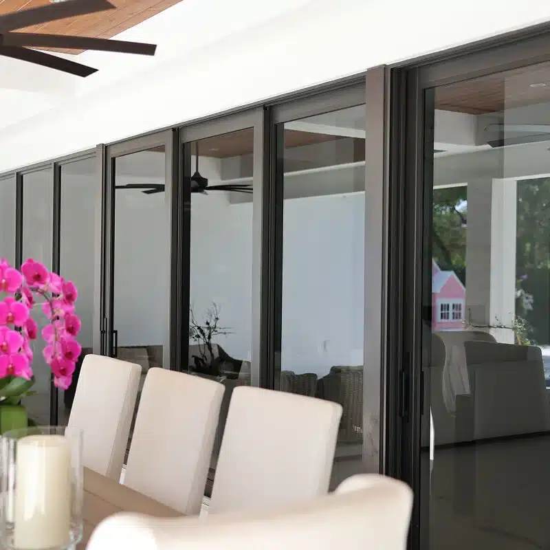 Dark-framed folding impact doors opening to a dining terrace