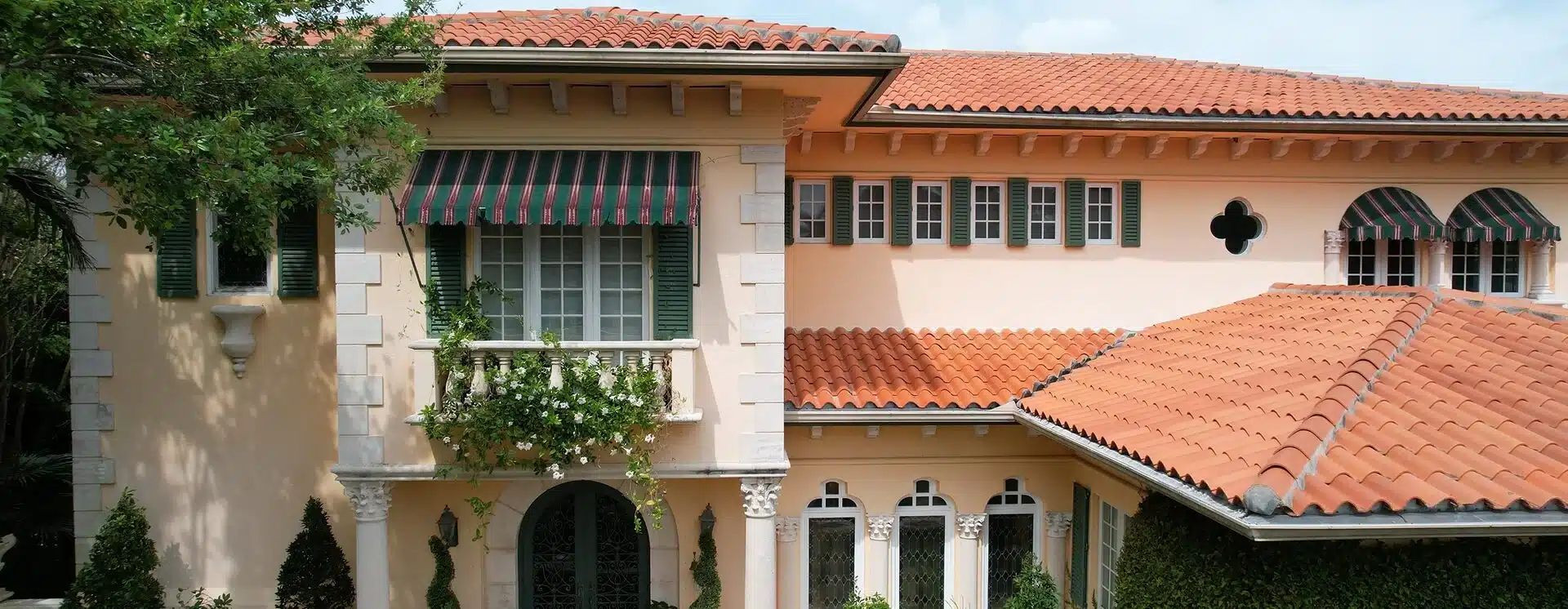 Mediterranean home with striped awnings over impact windows